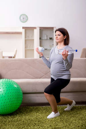 Aged pregnant woman doing exercises at homeの写真素材