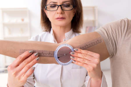 Female doctor checking patients joint flexibility with goniometerの写真素材