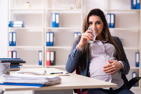 Young pregnant woman working in the officeの写真素材