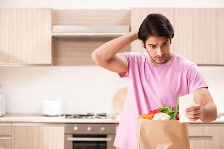 Young handsome man with vegetables in the kitchenの写真素材