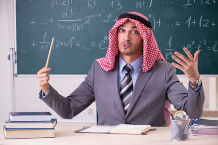 Arab teacher wearing suit in front of chalkboardの写真素材
