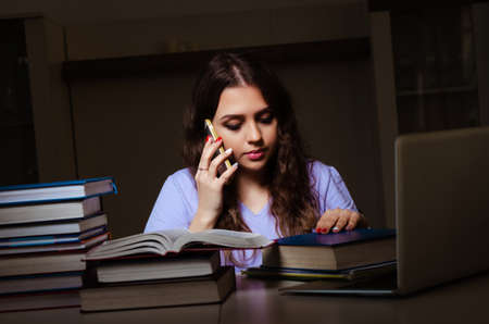 Young female student preparing for exams late at homeの写真素材