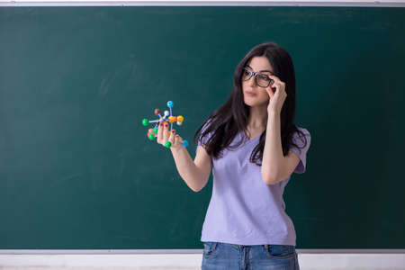 Young female teacher student in front of green board