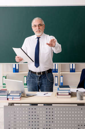 Aged male teacher in front of chalkboardの写真素材