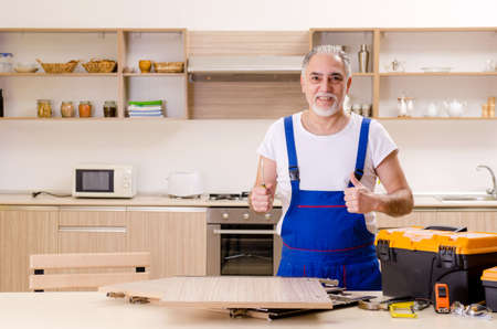 Aged contractor repairman working in the kitchenの写真素材