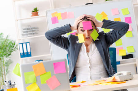 Young female employee in conflicting priorities conceptの写真素材