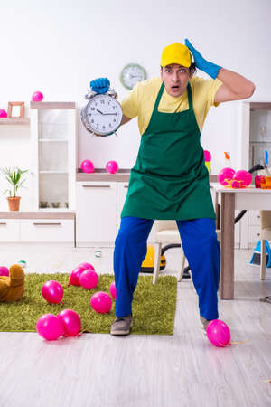 Young male contractor doing housework after partyの写真素材