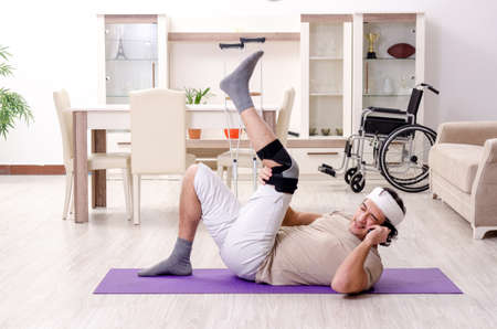 Injured young man doing exercises at homeの写真素材