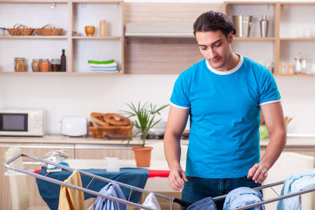Young man husband doing clothing ironing at homeの写真素材