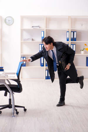 Young male employee in the office in time management conceptの写真素材
