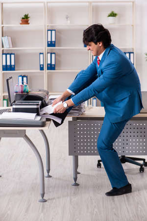 Young employee making copies at copying machineの写真素材