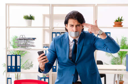 Young male employee with tape on the mouthの写真素材