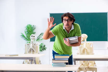 Funny male student in the classroom with skeletonの写真素材