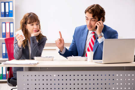 Two colleagues having lunch break at workplaceの写真素材