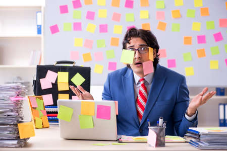 Young male handsome employee in conflicting priorities conceptの写真素材