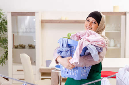 Woman in hijab doing clothing ironing at homeの写真素材