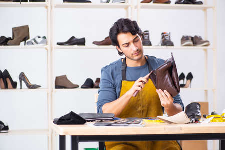 Young man repairing shoes in workshop
