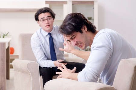 Young male patient discussing with psychologist personal problemの写真素材