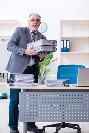 Aged male employee unhappy with excessive workの写真素材