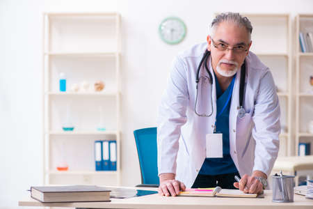 Old male doctor working in the clinicの写真素材