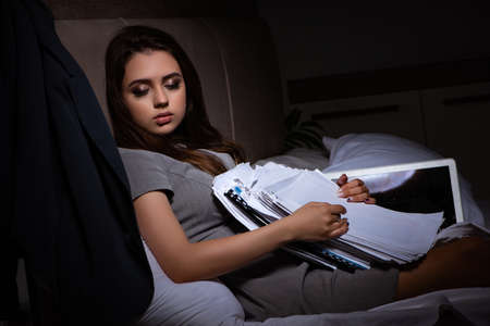 Tired businesswoman working overtime at home at nightの写真素材