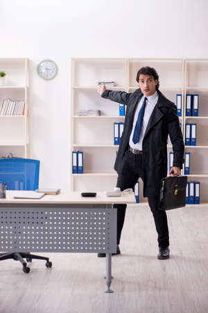 Young male employee in the office in time management conceptの写真素材