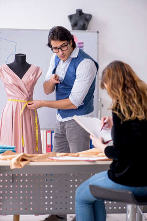 Young male tailor teaching female studentの写真素材