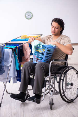 Young man in wheel-chair doing ironing at homeの写真素材