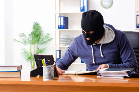 Male thief in balaclava in the officeの写真素材