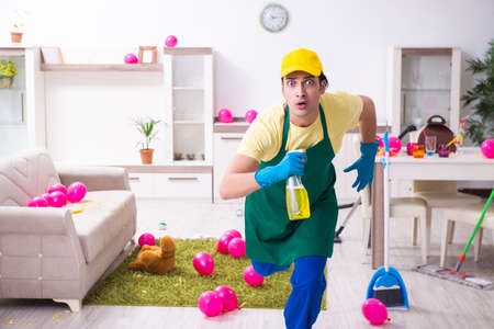 Young male contractor doing housework after partyの写真素材