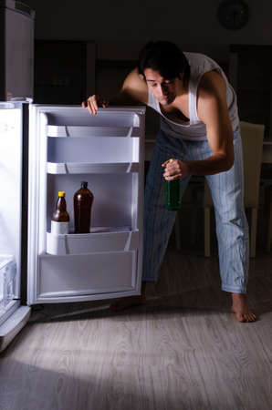 Man breaking diet at night near fridgeの写真素材
