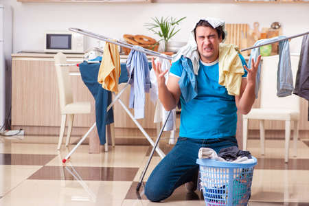Young man husband doing clothing ironing at homeの写真素材