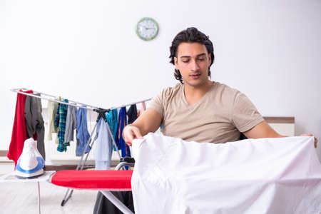 Young man in wheel-chair doing ironing at homeの写真素材