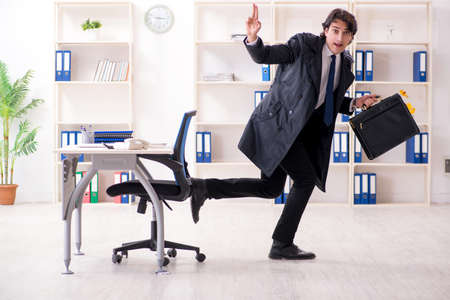 Young male employee in the office in time management conceptの写真素材