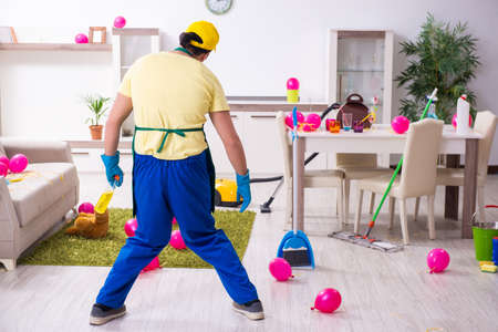 Young male contractor doing housework after partyの写真素材