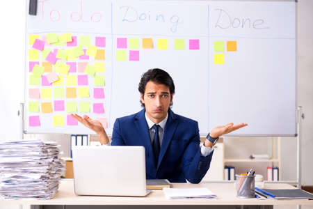 Young handsome employee in front of whiteboard with to-do listの写真素材