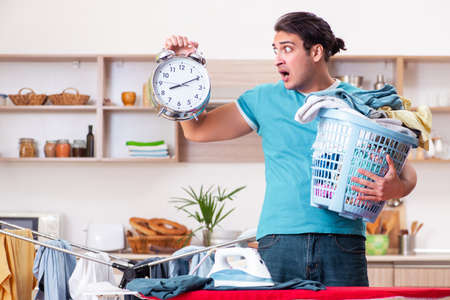 Young man husband doing clothing ironing at homeの写真素材