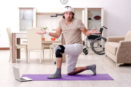 Injured young man doing exercises at homeの写真素材