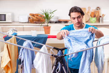 Young man husband doing clothing ironing at homeの写真素材
