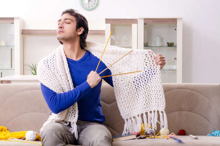 Young good looking man knitting at homeの写真素材