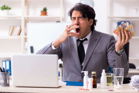 Man with flu working in the officeの写真素材