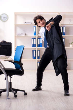 Young male employee in the office in time management conceptの写真素材