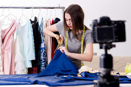 Young beautiful female tailor recording video for her blogの写真素材