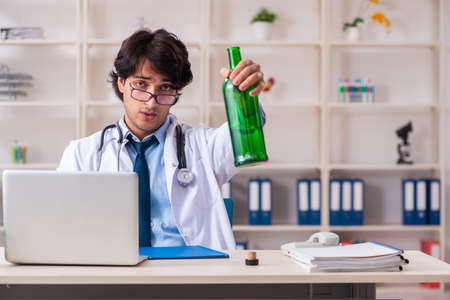 Young male doctor drinking in the officeの写真素材