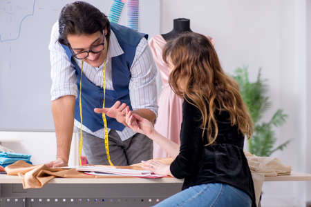 Young male tailor teaching female studentの写真素材