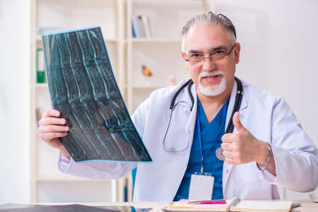 Old male doctor working in the clinic