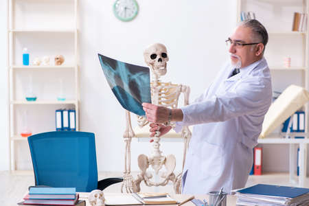 Aged male doctor with skeleton