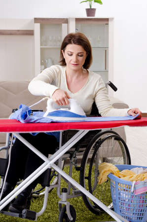 Woman in wheelchair ironing at homeの写真素材