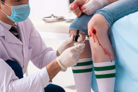 Leg injured young woman visiting male doctorの写真素材