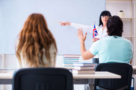 Old female english teacher and students in the classroomの写真素材